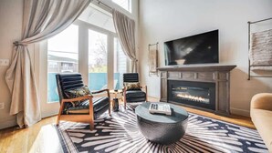 Una sala de estar con chimenea, un televisor de pantalla plana grande y dos sillones.