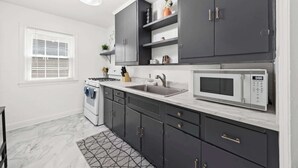 Una cucina moderna con mobili scuri, un forno a microonde, un lavello e un piano cottura.