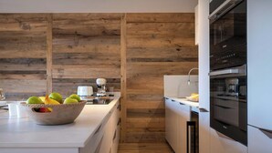 A modern kitchen with wooden paneling, a white countertop, and stainless steel appliances.
