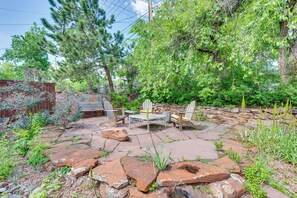 Eine Terrasse mit Steinboden, Holzmöbeln und umgebender Bepflanzung.