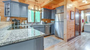 A modern kitchen with granite countertops, stainless steel appliances, and wooden paneling.