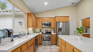 A modern kitchen with wooden cabinets, stainless steel appliances, and a tiled backsplash. - Explore Ramona's Vineyards: Tranquil Home w/ Yard (Ramona)
