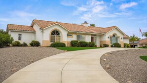 A two-story house with a curved driveway, a front lawn, and a flag in the background. - Explore Ramona's Vineyards: Tranquil Home w/ Yard (Ramona)