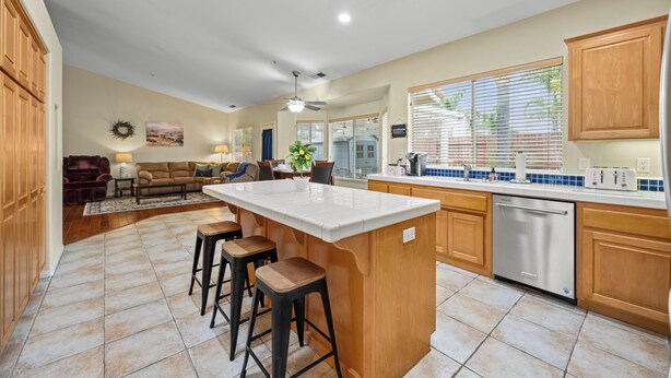 A spacious kitchen with a large island, wooden cabinets, and a dishwasher. - Explore Ramona's Vineyards: Tranquil Home w/ Yard (Ramona)