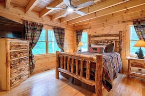 A log cabin bedroom with a bed, a dresser, a nightstand, and a ceiling fan. - Bear Pines charming 3 bdrm cabin, Hot Tub, WiFi, in scenic South Bloomingville (South Bloomingville)