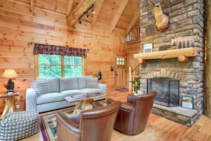 L’intérieur d’une cabane en rondins, avec une cheminée en pierre, des murs en bois, un canapé et une table basse.