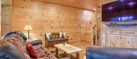 A wooden interior with a sofa, a coffee table, and a television.