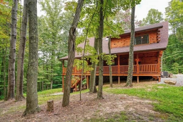 Une cabane dotée d’une terrasse, entourée d’arbres.