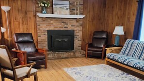 Una sala de estar acogedora con chimenea, sillones de cuero, un sofá y un tapete estampado.