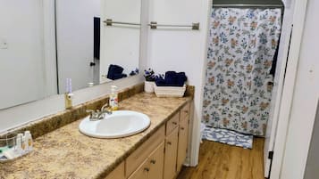 A bathroom with a sink, mirror, towel rack, and shower curtain.