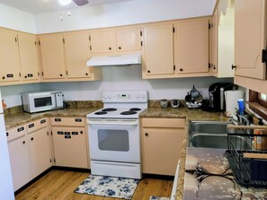 A kitchen with beige cabinets, a white stove, a microwave, and a sink. - 3-bedroom house in awesome Corinth with WiFi, AC. No cleaning fees (Corinth)