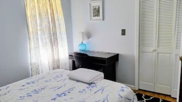 Una camera da letto con un letto, una scrivania, una sedia, una lampada e un armadio.