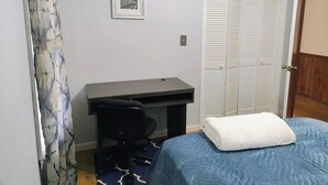 Un dormitorio con cama, escritorio y armario.
