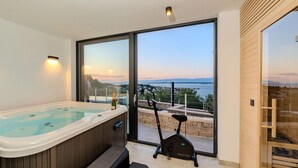 Een moderne badkamer met een jacuzzi, een loopband en een prachtig uitzicht op een meer en bergen.