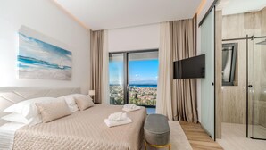 Een slaapkamer met een groot bed, een televisie en uitzicht op een stadsgezicht.