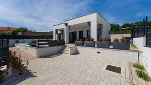 Une terrasse extérieure moderne avec une piscine, des coins salon et des plantes en pot.