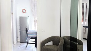 A room with a dining table, chairs, a refrigerator, and a mirror. - Michelle apartment with private parking (La Spezia)