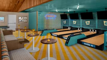 A billiards room with multiple tables and a neon sign.