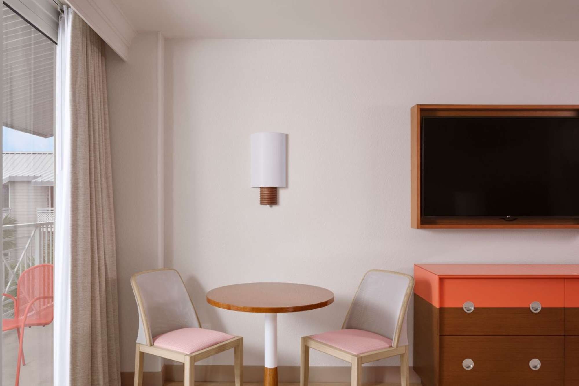 Ett hotellrum med ett runt bord, två stolar, en tv och en byrå.