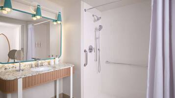 A bathroom with a sink, mirror, and shower.
