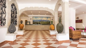 A hotel lobby with a checkered floor, a reception desk, and a seating area with a pink sofa. - Hostel Boutique & Beach Club Agua y Fuego - Adults Only (Cancun)