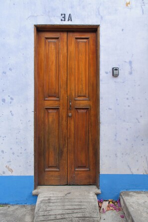 Une porte à deux battants en bois, surmontée du numéro « 3A », est encastrée dans un mur simple et sans ornements, avec une plinthe bleue.