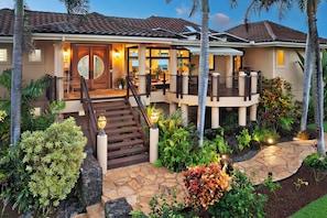 A two-story house with a stone pathway, a wooden staircase, and a well-maintained garden.
