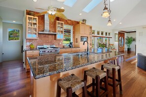 Una cocina amplia con una isla central, taburetes de madera y un ventilador de techo.