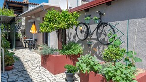 A narrow stone-paved courtyard with potted plants, a bicycle mounted on a wall, and a small outdoor seating area. - 1 bedroom beautiful apartment in Pula (Pula)