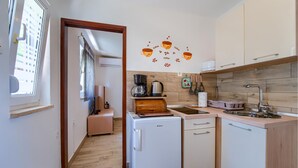 A compact kitchen with a coffee maker, kettle, and toaster. A small refrigerator is visible, and the kitchen has wooden cabinets. - 1 bedroom beautiful apartment in Pula (Pula)