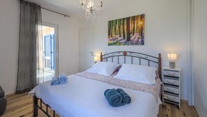 A bedroom with a bed, a chandelier, a painting of a forest, and a bedside table with storage drawers. - Amazing home in Svetvincenat with WiFi (Svetvincenat)