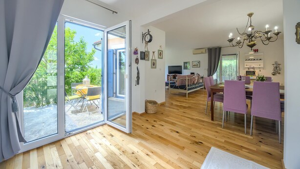 A spacious living area with a wooden floor, a dining table with chairs, a TV, and a chandelier. - Amazing home in Svetvincenat with WiFi (Svetvincenat)