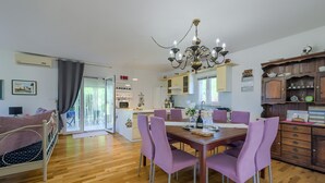 A modern kitchen with a dining table, purple chairs, and a chandelier. - Amazing home in Svetvincenat with WiFi (Svetvincenat)