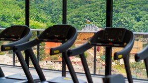 Exercise equipment with a view of a lush green landscape and a building with a statue. - The Spot One - Luxo e acesso direto ao Balneário Shopping (Balneário Camboriú)