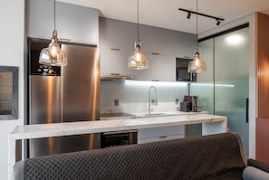 A modern kitchen with stainless steel appliances, a marble countertop, and pendant lighting. - The Spot One - Luxo e acesso direto ao Balneário Shopping (Balneário Camboriú)