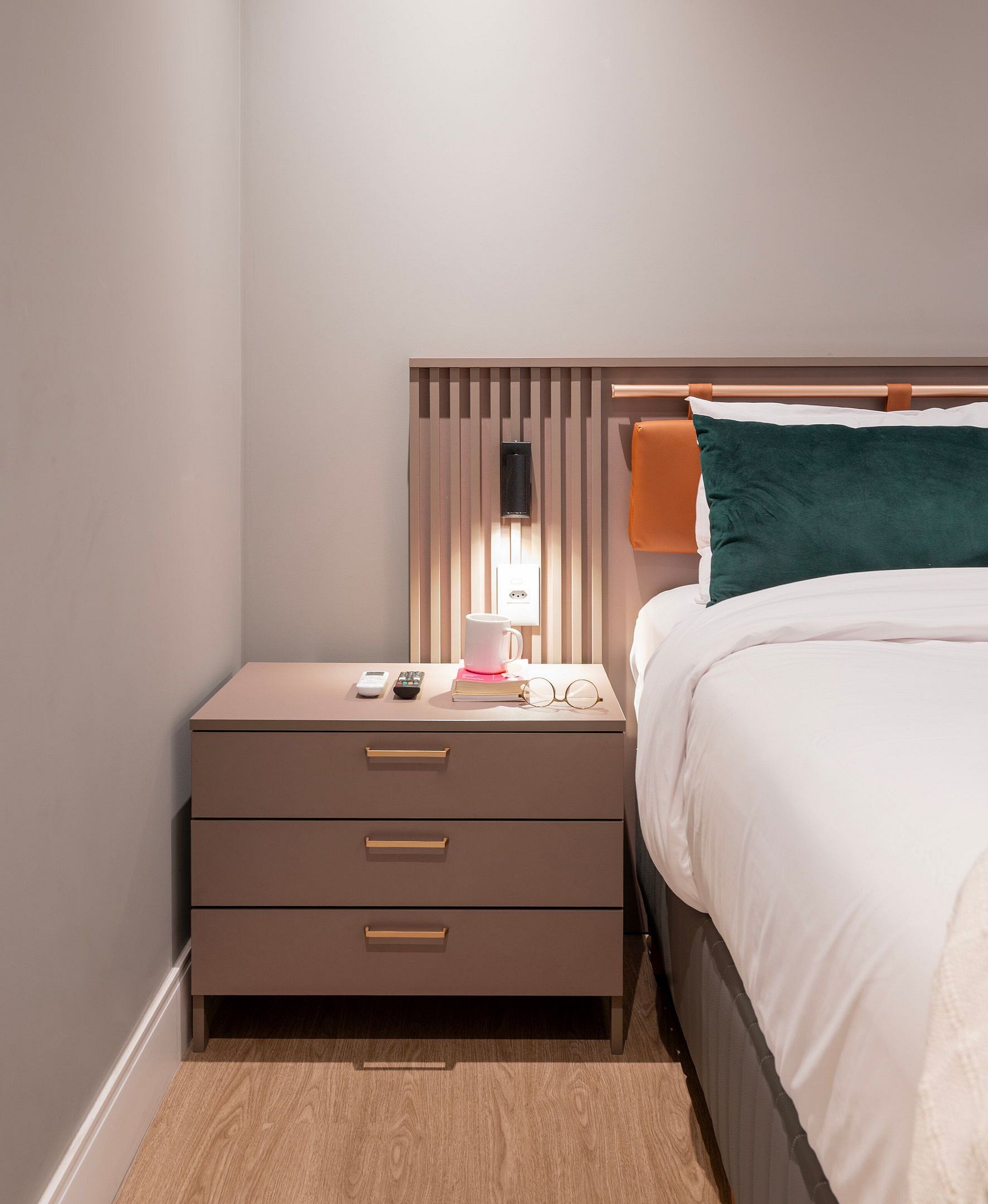A neatly arranged bedroom with a bed, bedside table, and a nightstand.