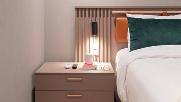 A neatly arranged bedroom with a bed, bedside table, and a nightstand.