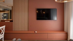 A modern living room with a large flat-screen TV mounted on the wall, a built-in bench with storage, and a pendant light fixture.