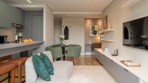 A modern kitchen with a dining area, a sofa, and a TV.