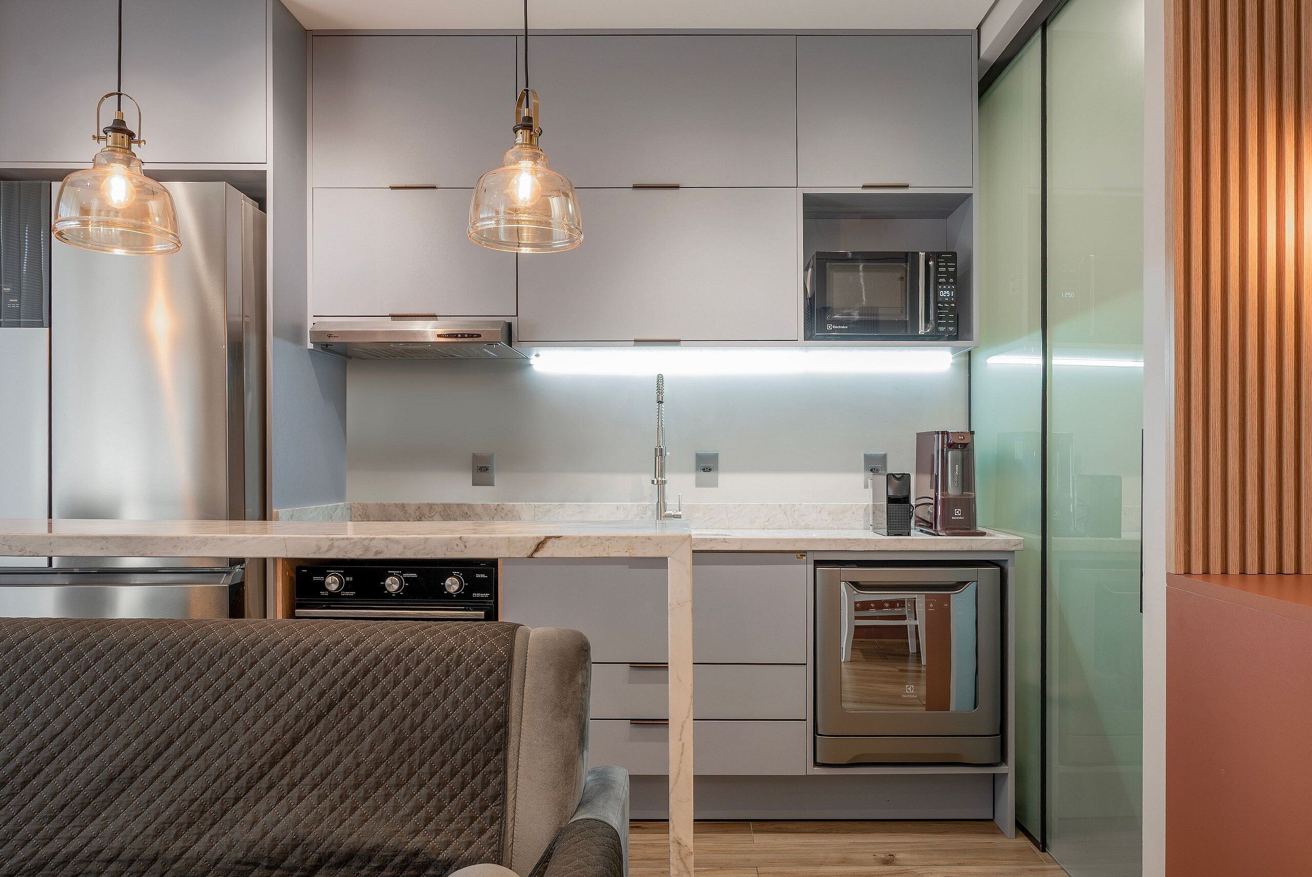 Una cocina moderna con electrodomésticos de acero inoxidable, encimera de mármol e iluminación colgante.