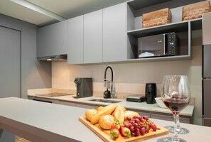 A modern kitchen with a built-in microwave, coffee maker, and a wine glass on the counter. - The Spot One - Luxo e acesso direto ao Balneário Shopping (Balneário Camboriú)