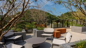 An outdoor seating area with modern furniture, a round table, and planters. - The Spot One - Luxo e acesso direto ao Balneário Shopping (Balneário Camboriú)