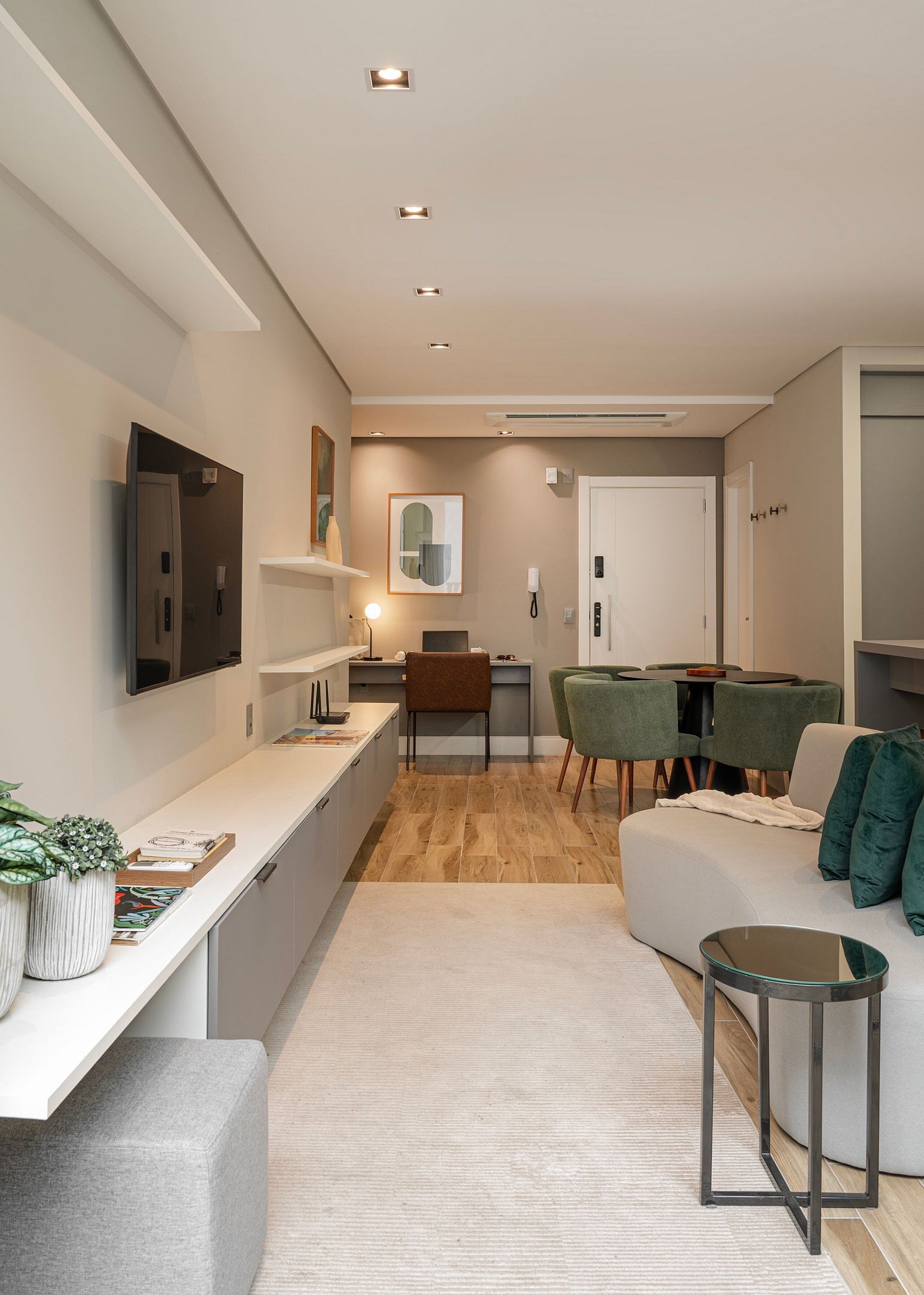 Una sala moderna con un sofá, una mesa de centro, un televisor montado en la pared y una zona de comedor con sillas y una mesa.