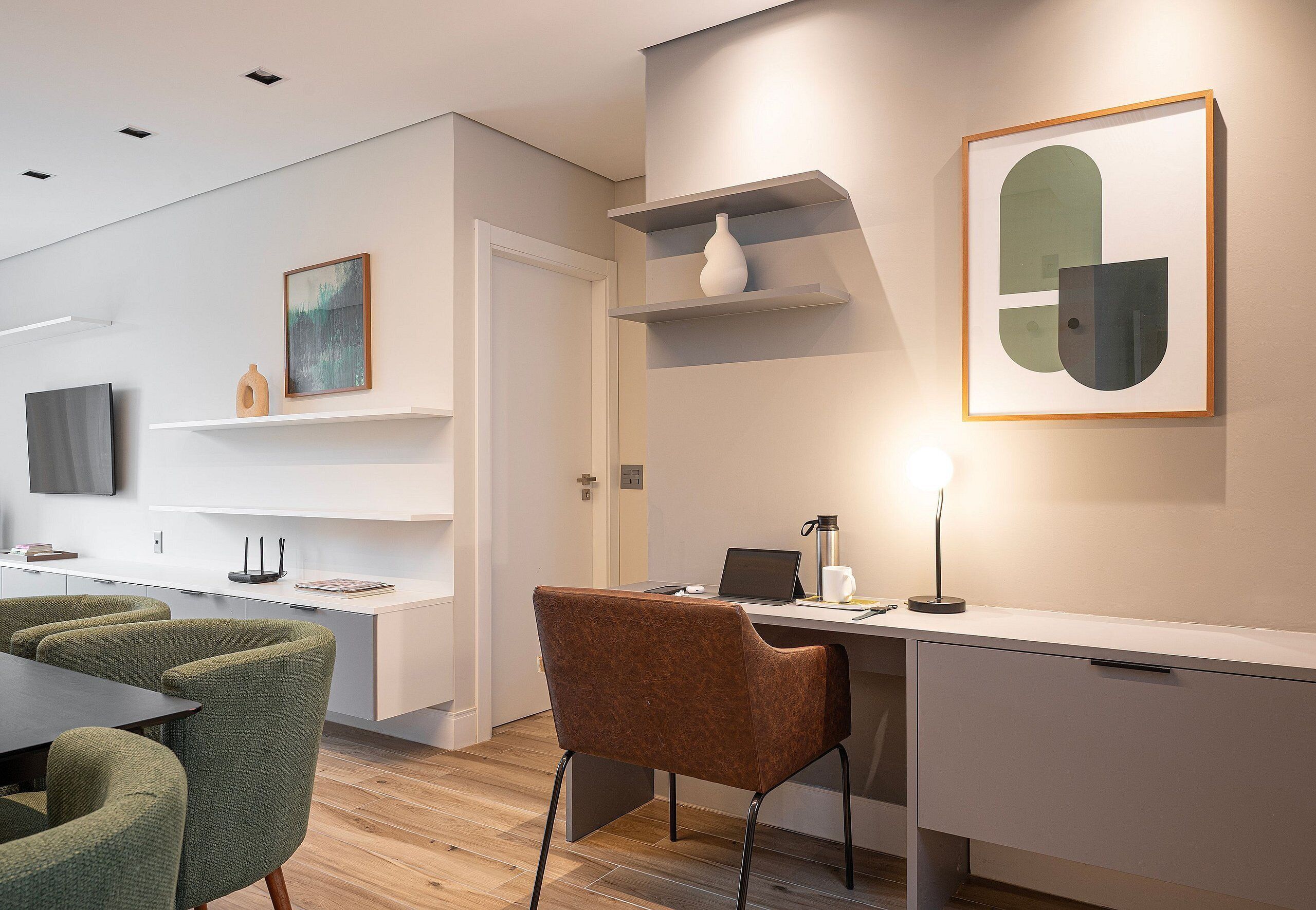 A modern interior with a dining area, a desk with a laptop, and artwork on the walls.