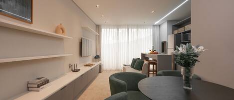 A modern living room with a dining area, a flat-screen TV mounted on the wall, and a large window with sheer curtains.