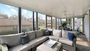 Een overdekt terras met een modulaire bank, een bijzettafeltje en uitzicht op de achtertuin.