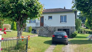 A house with a paved driveway leading to a garage, surrounded by greenery and a fenced garden. - Gite Detached house sleeps 6 Pets welcome Wifi lake 10mn (Lacapelle-Viescamp)