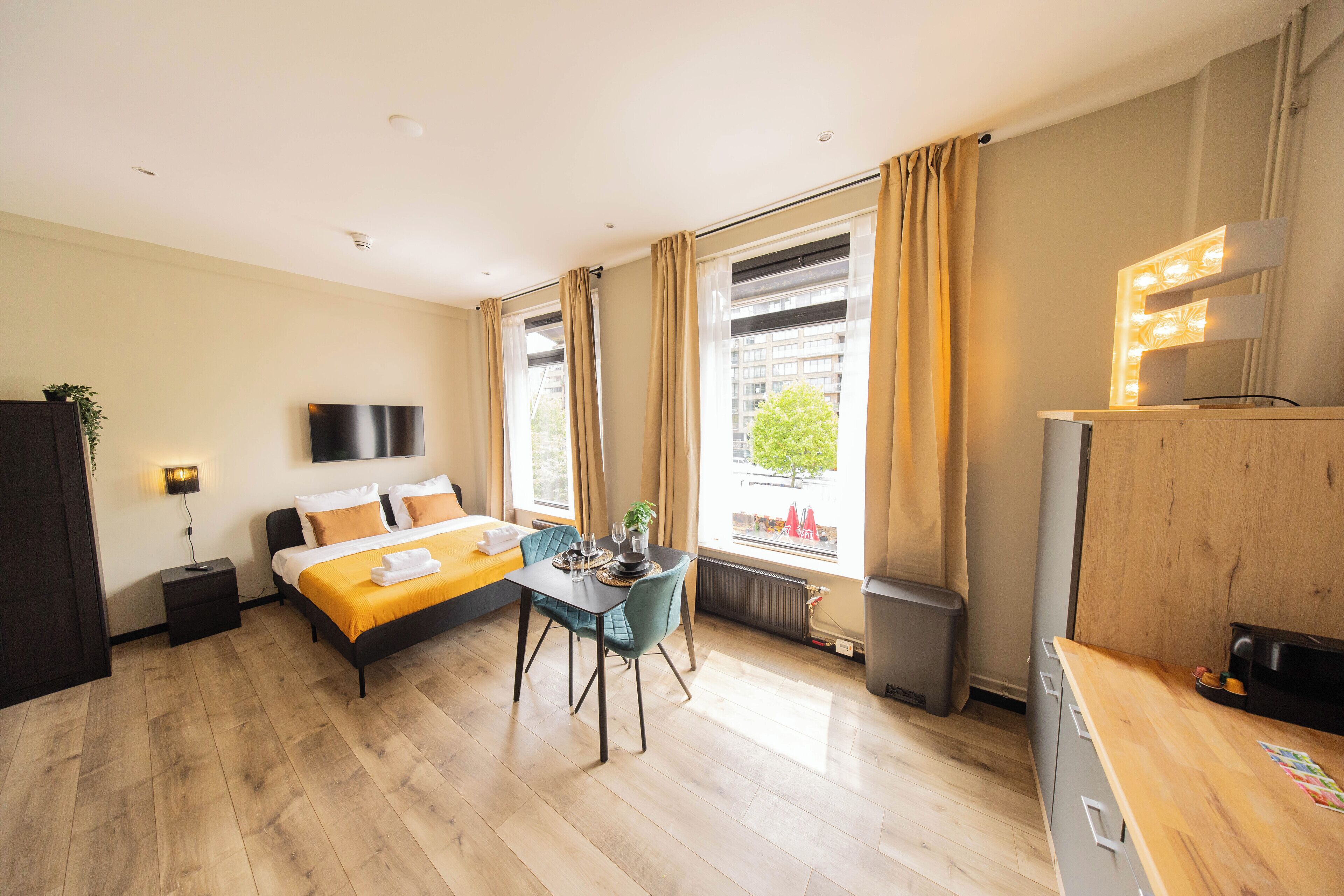 Une chambre d’hôtel moderne équipée d’un lit, d’une table à manger, d’un téléviseur et offrant une vue sur la ville.