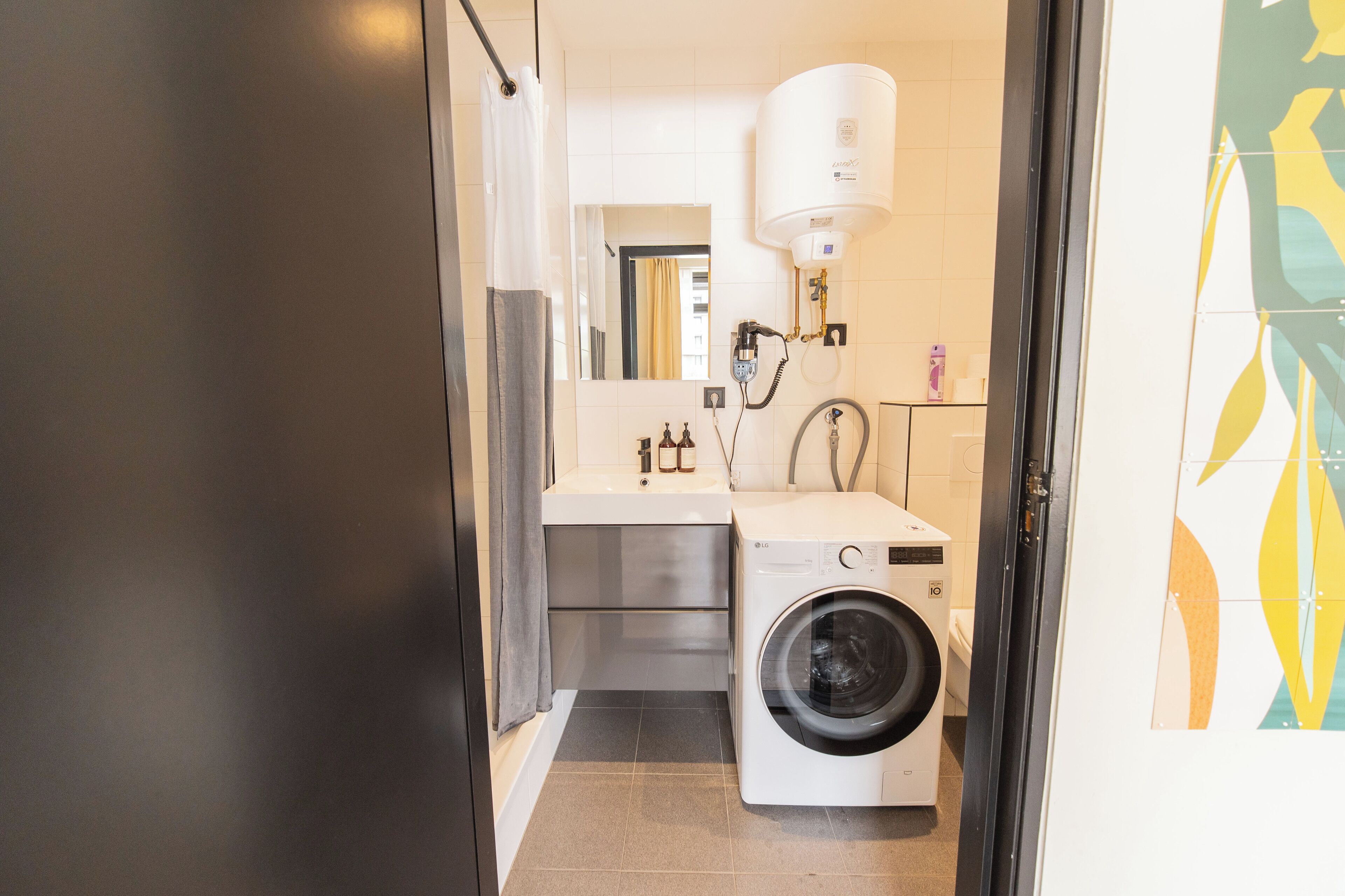 Een kleine badkamer met een wasmachine, wastafel en toilet.