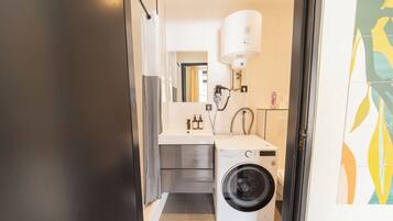 Een kleine badkamer met een wasmachine, wastafel en toilet.